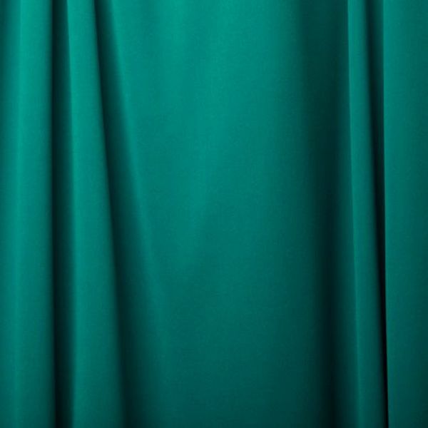 Turquoise curtain with gentle folds and shadows.