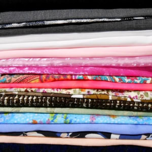 Colourful folded fabric stack with diverse patterns.