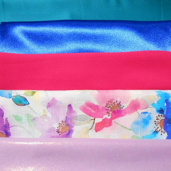 Stacked colourful fabrics, shiny and floral patterns.